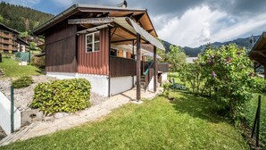 Un chalet en bois doté d’un balcon, entouré d’un jardin et avec une vue sur les montagnes.