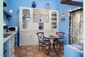 A kitchen with a white cabinet, two chairs, a dining table, and a microwave.