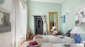 Ein Schlafzimmer mit zwei Betten, einem Spiegel, einer Lampe und einem Gemälde an der Wand.