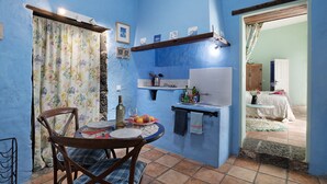 Eine kompakte Küche mit Essbereich, ausgestattet mit einem Tisch und Stühlen, einer kleinen Arbeitsfläche und einem Fenster mit Vorhängen.