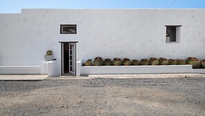 Un bâtiment à la façade blanche, avec une porte et une rangée de cactus.