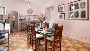 Un coin repas avec une table dressée pour quatre personnes, des chaises en bois, un vase rempli de fleurs et une horloge au mur.