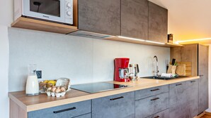 Une cuisine moderne équipée d’un four à micro-ondes encastré, d’une machine à café rouge et d’un évier.