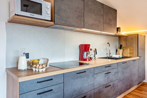 A modern kitchen with a built-in microwave, a red coffee maker, and a sink.
