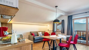 Une cuisine moderne dotée d’une cuisinière intégrée, un coin repas avec une table et des chaises, un canapé et un balcon offrant une vue agréable.