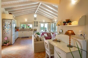 A spacious kitchen with a high ceiling, a dining area with a table and chairs, and a living room with a sofa and a lamp. - Villa "Aloni" with Sea View, Private Pool & Wi-Fi (Paxoi)