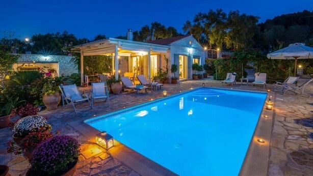 Ein Schwimmbecken mit Liegestühlen und einer überdachten Terrasse.