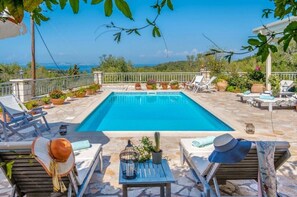 A pool area with lounge chairs, potted plants, and a view of the sea. - Villa "Aloni" with Sea View, Private Pool & Wi-Fi (Paxoi)