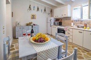 A kitchen with a dining table set for two, a refrigerator, microwave, and a stove.