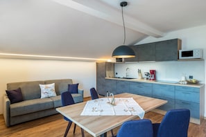A modern kitchen with grey cabinets, a microwave, and a dining area with a table and chairs. - Apartment 'Morodeserhof Apt Bühlen 1' with Mountain View, Shared Terrace and Wi-Fi (Castelrotto)