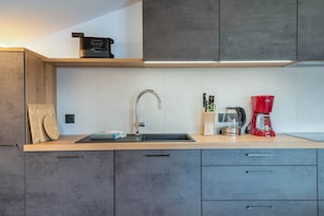 A modern kitchen with a stainless steel sink, a red coffee maker, and a built-in range hood. - Apartment 'Morodeserhof Apt Bühlen 1' with Mountain View, Shared Terrace and Wi-Fi (Castelrotto)