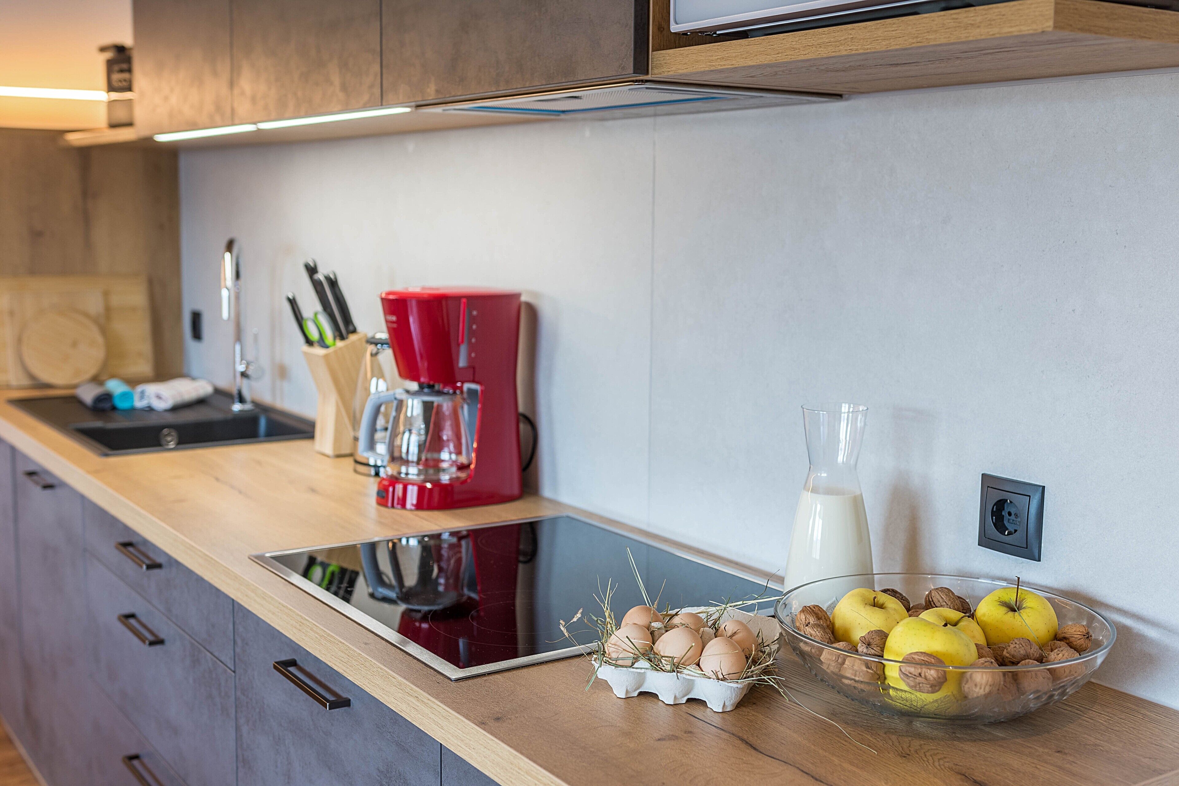 Cucina dal design moderno, con forno a incasso, macchina del caffè e una ciotola con frutta secca sul piano di lavoro.