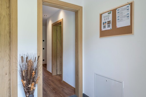 A hallway with a wooden door, a bulletin board with notices, and a decorative vase with dried plants. - Apartment 'Morodeserhof Apt Bühlen 1' with Mountain View, Shared Terrace and Wi-Fi (Castelrotto)