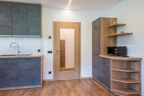 A modern kitchen with grey cabinets, a wooden door, and a built-in microwave shelf.