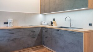 Una cocina moderna con gabinetes grises, encimera de madera, cafetera, tostadora y un lavamanos.