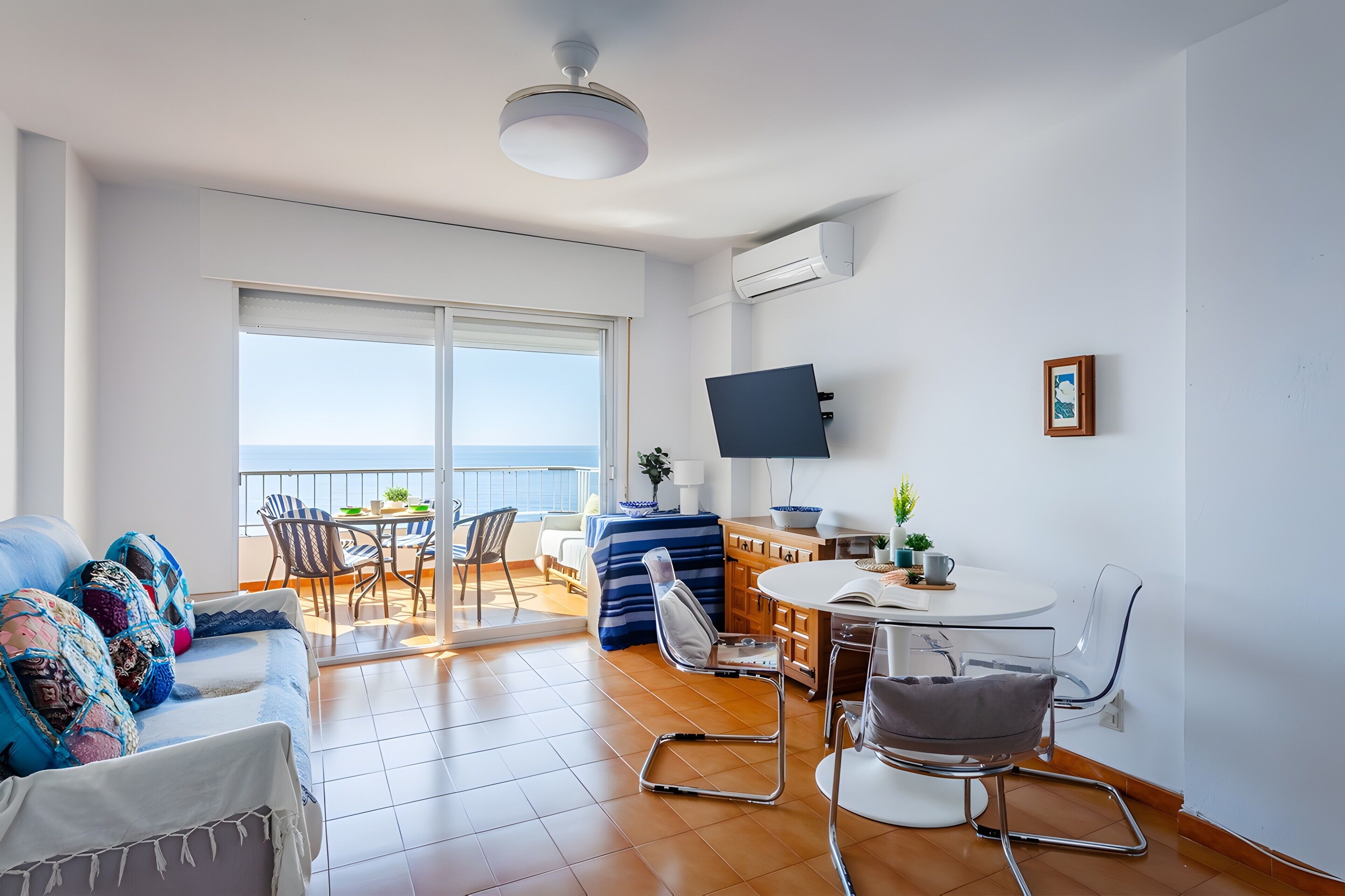 Una sala moderna con sofá, sillas, mesa de comedor y televisor.