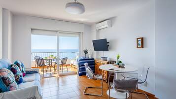 Una sala moderna con sofá, sillas, mesa de comedor y televisor.
