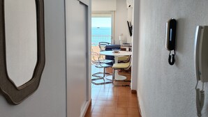 A hallway with a tiled floor, a mirror, a telephone, and a view of the sea through a balcony door. - Vacation Apartment 'Epsilon 2 4f Primera Línea De Playa' with Sea View & Shared Pool (Almuñecar)