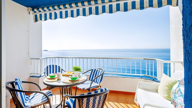 A balcony with a view of the sea, a table with chairs, and a white sofa. - Vacation Apartment 'Epsilon 2 4f Primera Línea De Playa' with Sea View & Shared Pool (Almuñecar)