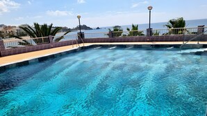 A clear swimming pool with a wooden deck, a metal railing, and a lamp post. - Vacation Apartment 'Epsilon 2 4f Primera Línea De Playa' with Sea View & Shared Pool (Almuñecar)