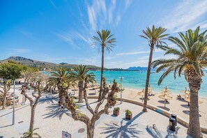 A beachside promenade with palm trees, beach umbrellas, and a view of the sea.