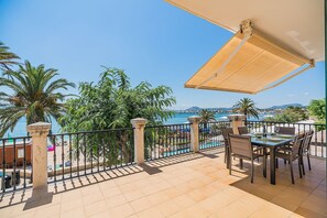 A balcony with a table and chairs, overlooking a pool and beach area.