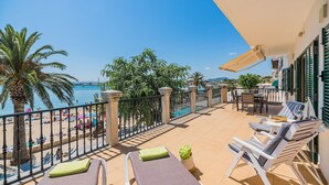 A balcony with a view of the beach, lounge chairs, and a table. - 'Pine Walk' Apartment with Sea Views, Wi-Fi and Air Conditioning (Pollensa)