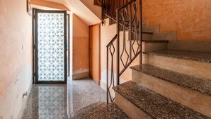 Una escalera con barandillas de metal, una puerta con diseño y una pared con textura.