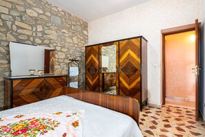 A bedroom with a bed, a dresser, a mirror, and a wardrobe.