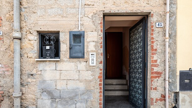 Entrada de un edificio con puerta, una ventana con reja de metal y un cartel con un número.