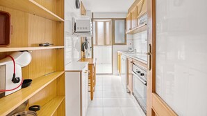 A narrow kitchen with wooden cabinets, a built-in oven, and a microwave. - Holiday Apartment 'Barlovento I' with Sea View, Terrace, Shared Pool & Wi-Fi (Xeraco)