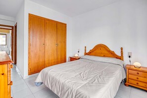 A bedroom with a wooden bed, a wardrobe, a nightstand, and a dresser.