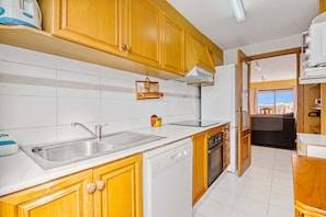 A compact kitchen with wooden cabinets, a dishwasher, and a sink.