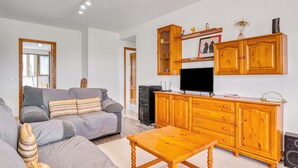 A living room with a sofa, wooden cabinet, television, and a small table. - Holiday Apartment 'Barlovento I' with Sea View, Terrace, Shared Pool & Wi-Fi (Xeraco)