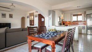A modern kitchen with a central island, a dining area with a wooden table and chairs, and a living area with a sofa. - Villa 'Kumusha' with Sea View, Pool, Garden & Wi-Fi (Kefalonia)