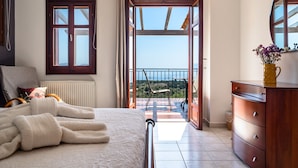 A bedroom with a bed, a dresser, a window, and a balcony with a view. - Villa 'Kumusha' with Sea View, Pool, Garden & Wi-Fi (Kefalonia)