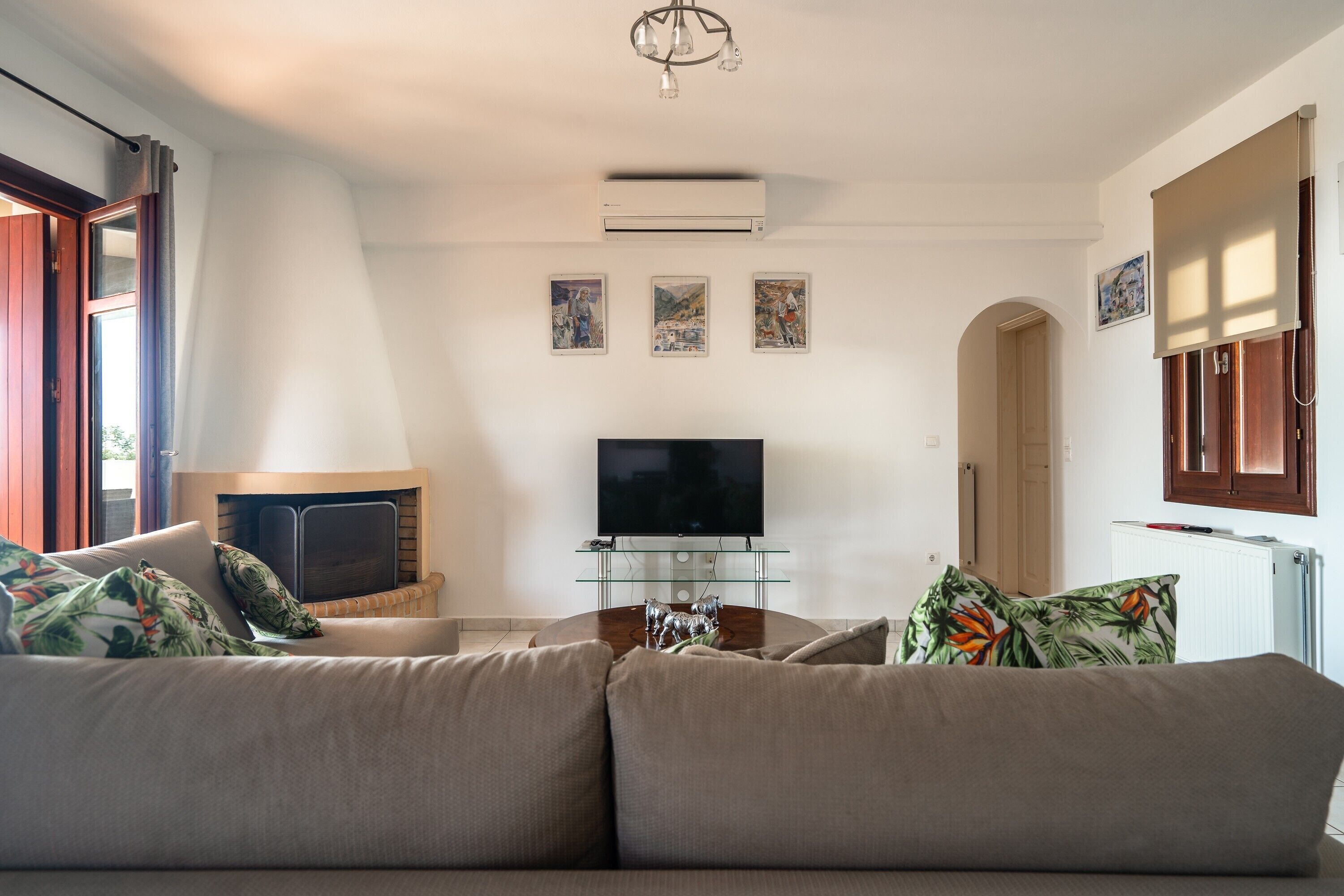 Een woonkamer met een bank, televisie, open haard en kunst aan de muur.
