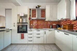 Une cuisine moderne avec des armoires blanches, une hotte de cuisinière en acier inoxydable et un dosseret carrelé.
