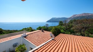 A rooftop terrace with a view of the sea and mountains.