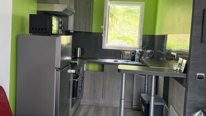 A compact kitchen with modern appliances, a window, and a red sofa. - Petit Villa Climatise A Moriani Plage (San-Nicolao)