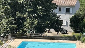 A swimming pool surrounded by lush greenery, with a house in the background. - Petit Villa Climatise A Moriani Plage (San-Nicolao)