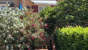 A building with a corrugated metal roof, a covered patio area, and a sign indicating a room number. - Petit Villa Climatise A Moriani Plage (San-Nicolao)