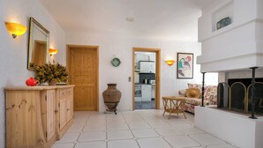 A spacious living area with a wooden cabinet, a large vase, and a sofa with a woven table. - Villa Euphoria Theologos Thassos (Θεολόγος)