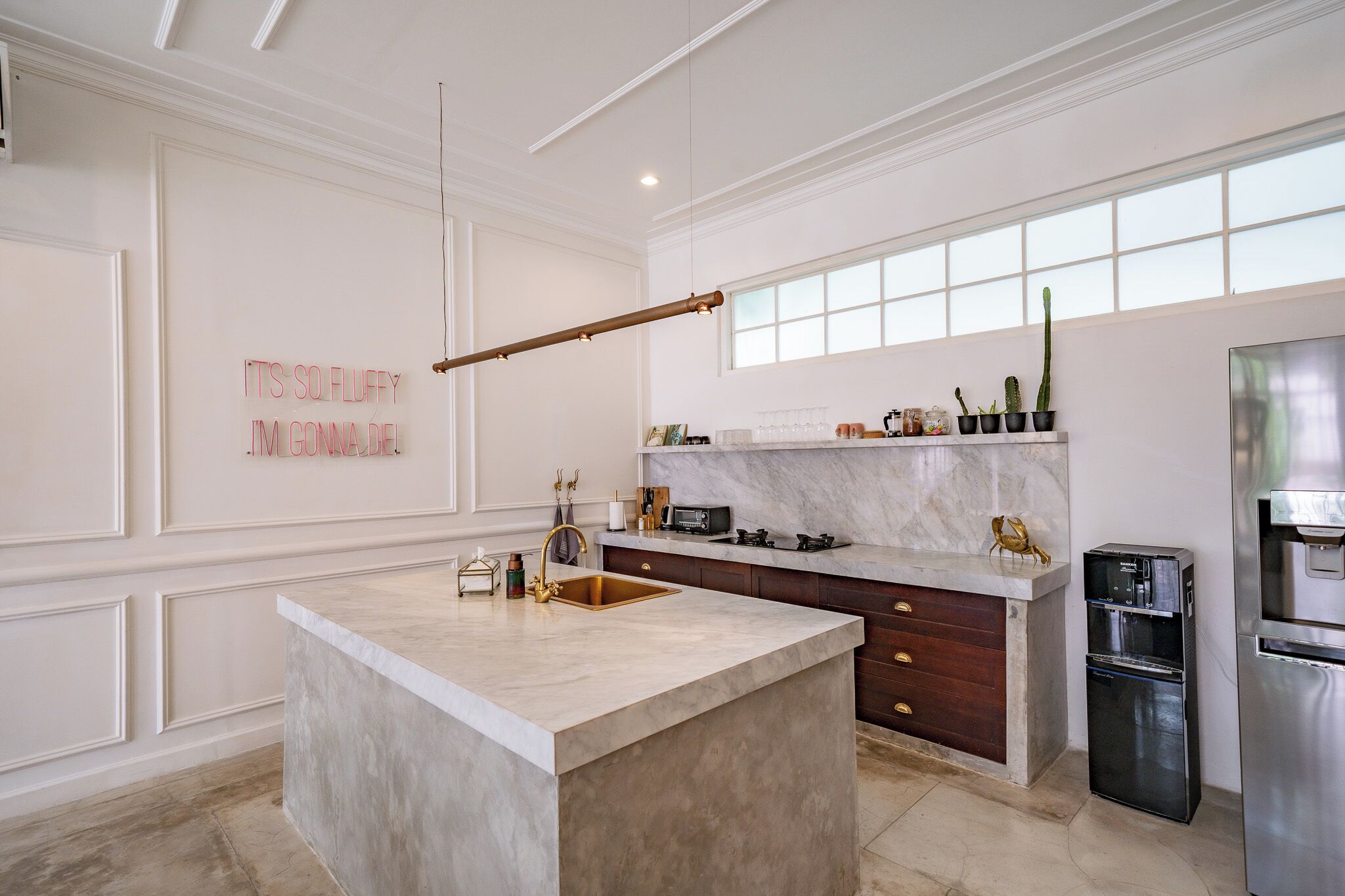 A modern kitchen with a marble island, stainless steel appliances, and a decorative wall sign.