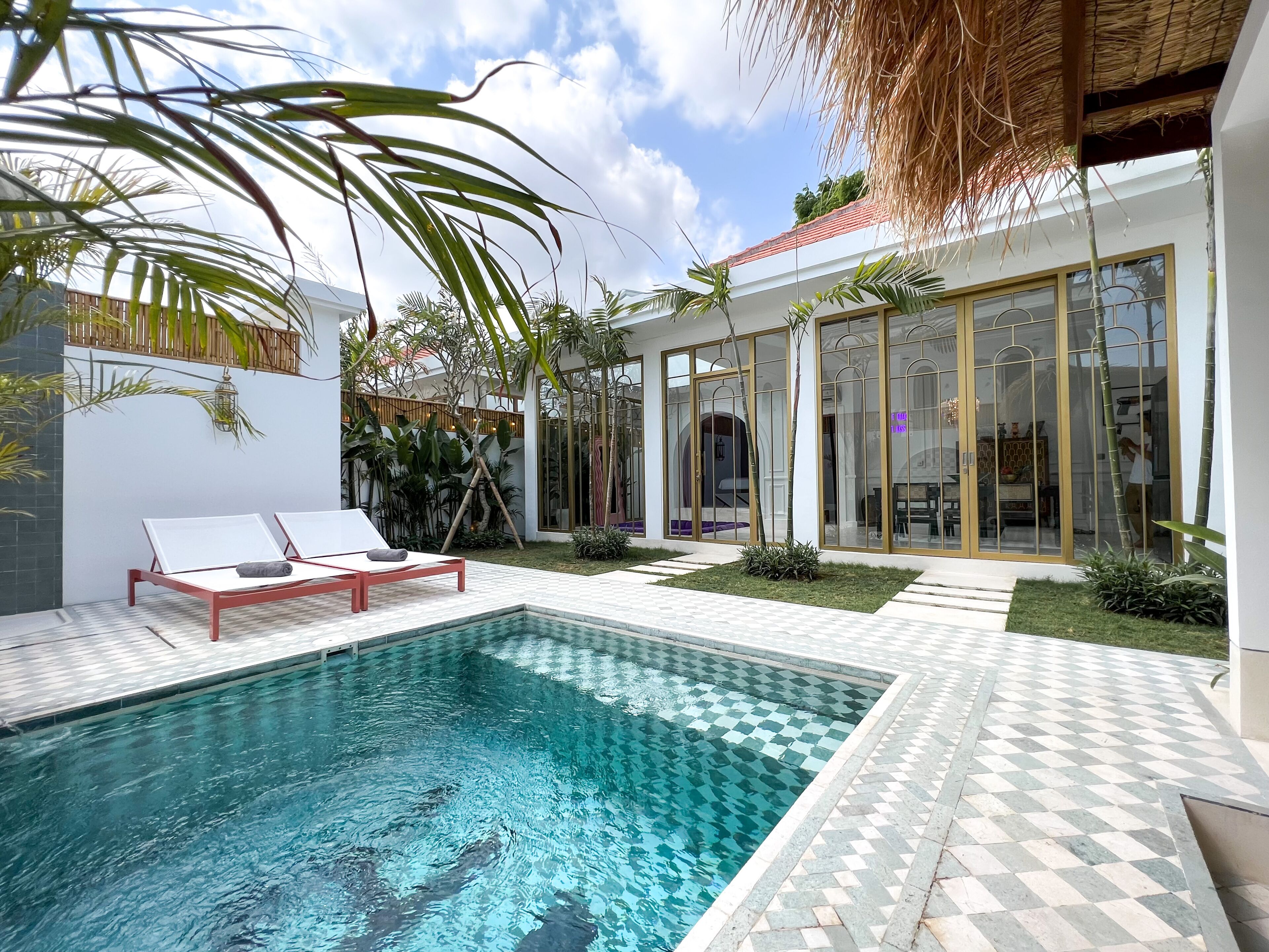 A modern outdoor pool area with lounge chairs, a clear blue pool, and a well-maintained garden with various plants.