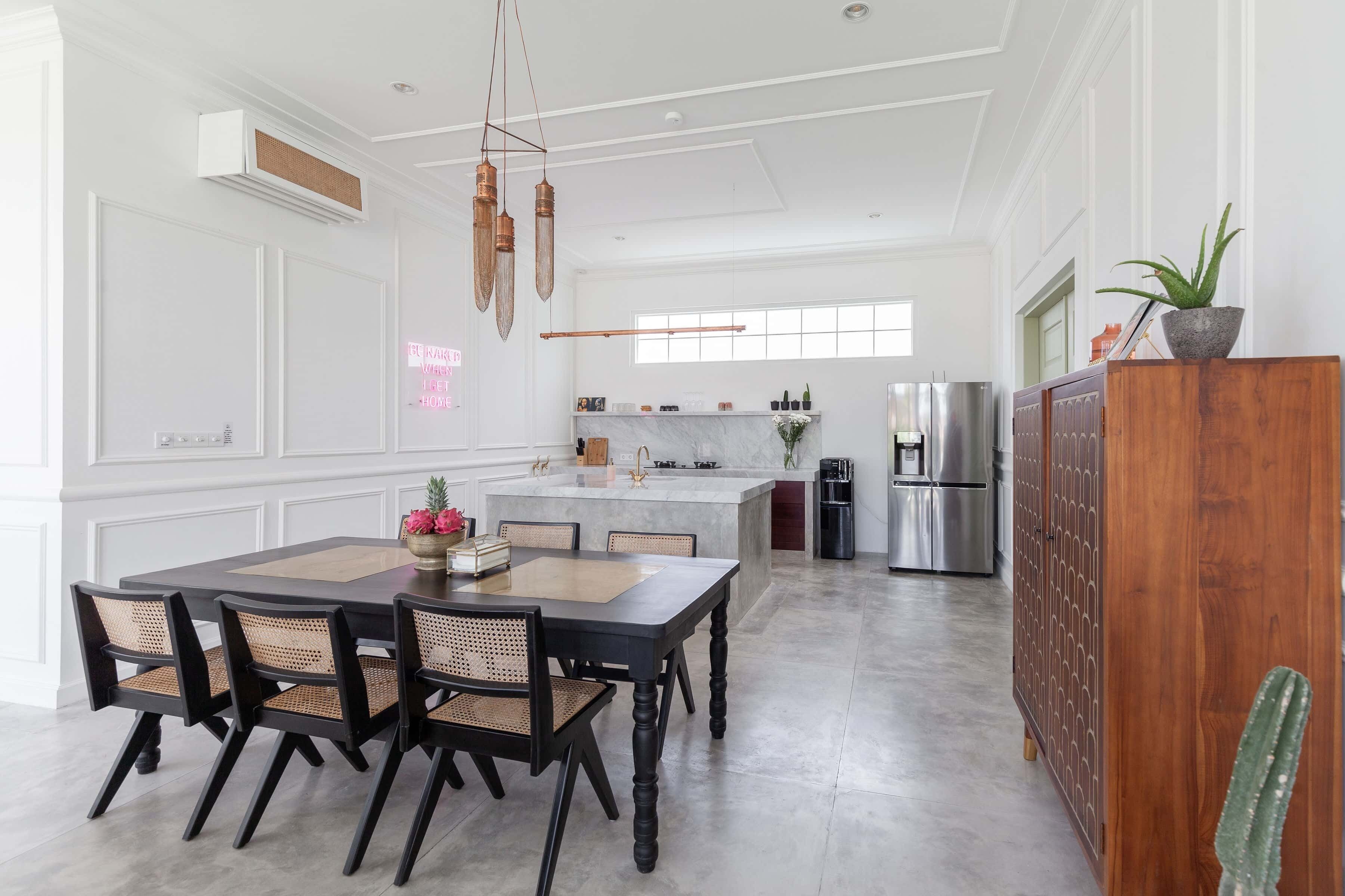 Een moderne keuken met een centraal eiland, roestvrijstalen apparatuur en een eethoek met een houten tafel en stoelen.