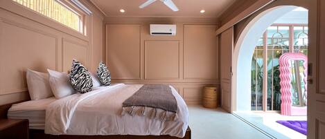 A bedroom with a bed, a ceiling fan, a window, and a door leading to a balcony.