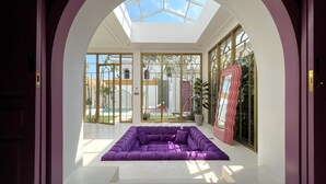Ein modernes Interieur mit einem violetten, modularen Sofa, großen Glasüren, die zu einem Außenbereich führen, und einem Oberlicht.