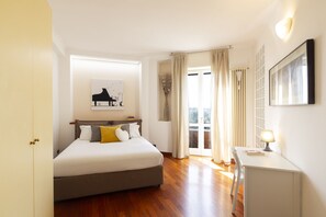 Une chambre à coucher avec un lit, une table de chevet et une vue sur l’extérieur.