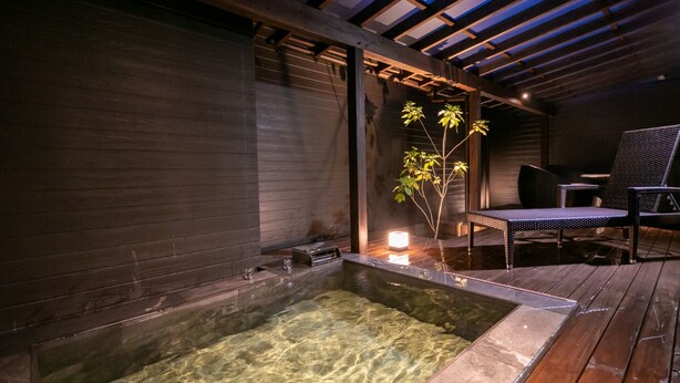 A hot tub area with clear water, wooden flooring, and a chair. - yumotoankiyohime (Kirishima)
